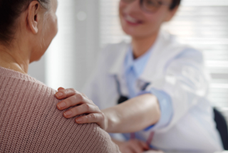 A smiling rheumatologist performing an exam on her patient